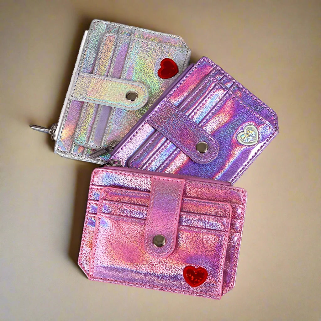 A showcasing of all three glitter wallets with hearts in the colors pink, silver, and purple on a plain background. 