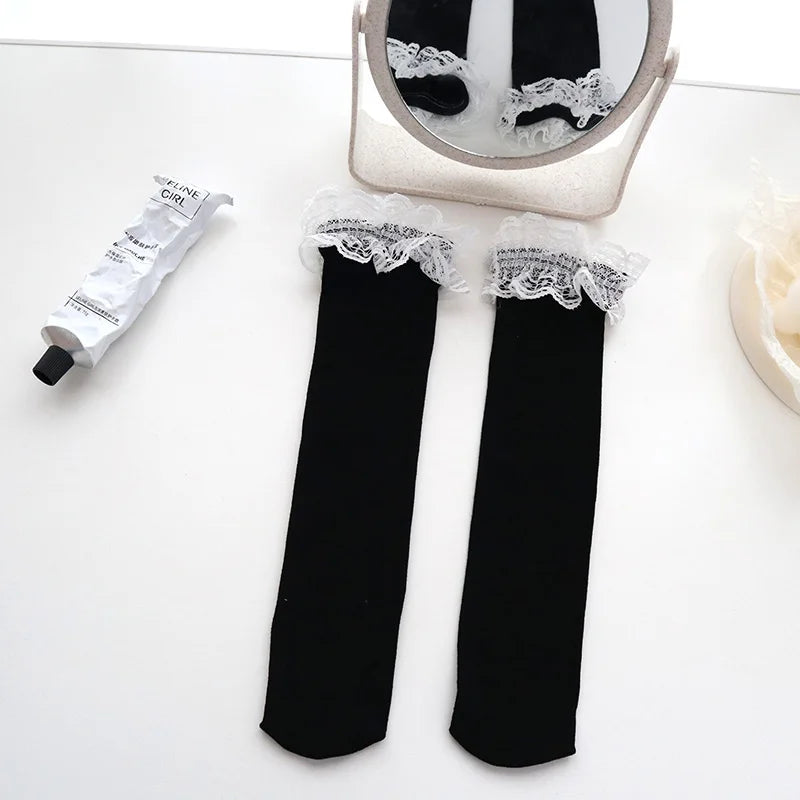 A showcasing of the Black Lace Ruffle Socks on a top. The lace ruffles are at the mouth of the socks. 