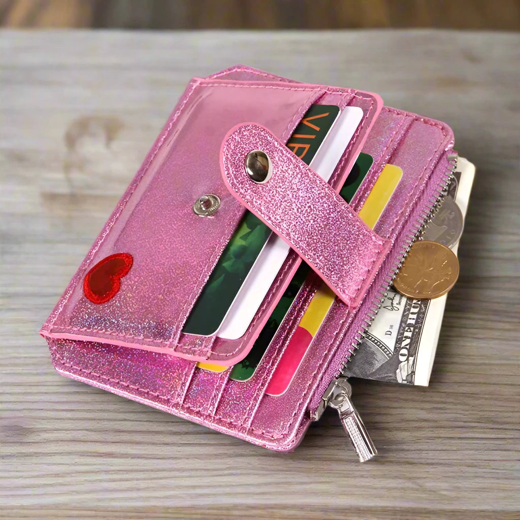 A showcasing of a Pink Glitter Wallet with a little red heart full to show how much you can actually fit in it sitting on a wooden coffee table. 