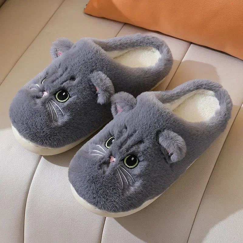 A showcase of the Gray Fuzzy Cat Unisex House Slippers on a white leather seat. This gray is more of a darker ashy gray with a blue gray tone in certain light.