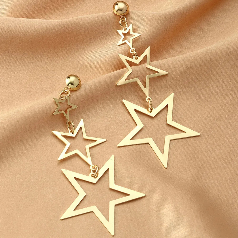 A showcasing of the gold version of the Kpop Inspired Triple Star Drop Earrings on a beautiful satin background.