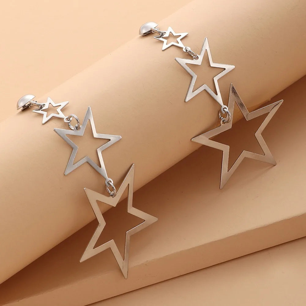 A showcasing of the silver version of the Kpop Inspired Triple Star Drop Earrings laid over a curved pole to show the mobility of the earrings.