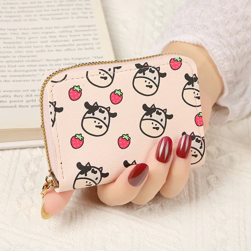 A showcase of the Light Pink Strawberry Cow Card Bag being held in a hand to show the size comparison. This print is some cute cows and strawberries all over a light pink card bag. 