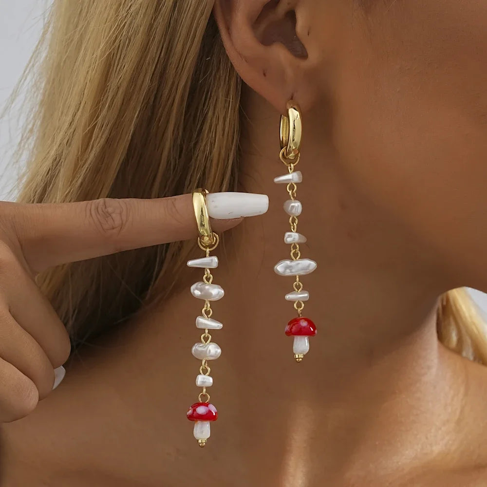 A showcasing of the medium length White Stone Mushroom Geometric Earrings on a model with one in her ear and the other held up by her finger to give a speculated view of the lenght.