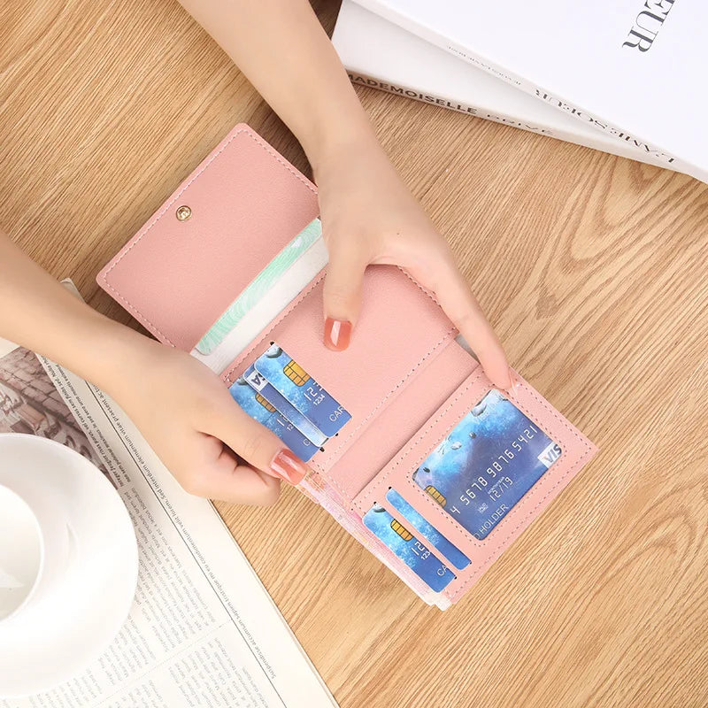 A showcasing of the open view of one of the light pink wallets showing the layout of the inside and filled with different things it can hold in the different spots offered.