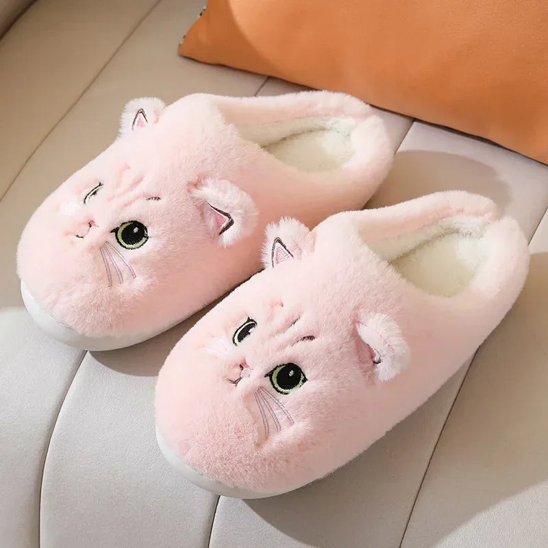 A showcase of the Pink Fuzzy Cat Unisex House Slippers on a white leather seat. This pink is more of a light baby pink. 