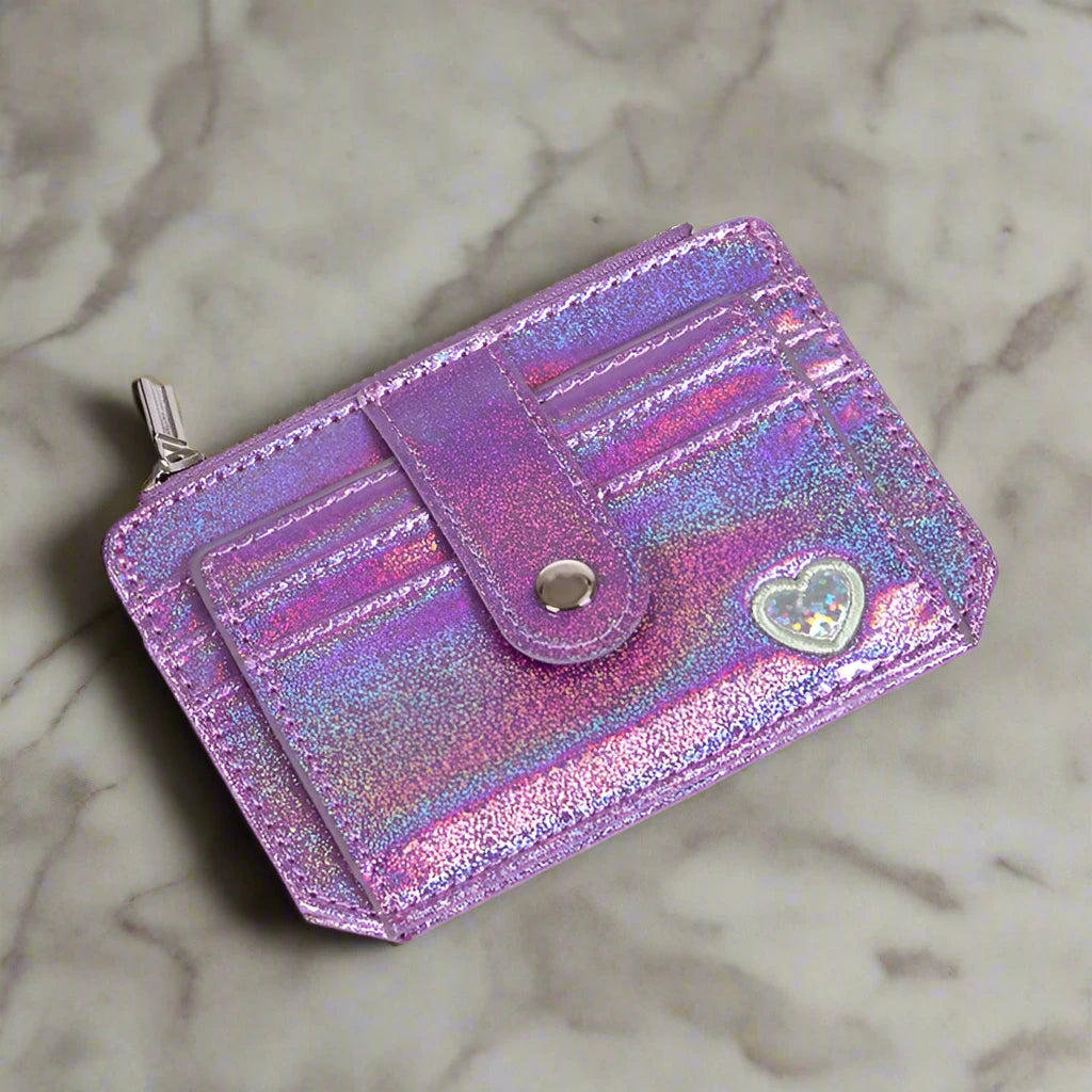 A showcasing of the Purple Glitter Wallet with a little white heart laid flat to show the front of the wallet. 