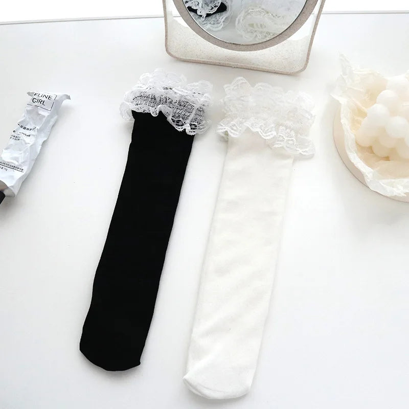 A showcasing of the Black Lace Ruffle Sock and the White Lace Ruffle Sock side by side on a white table to show comparison. 