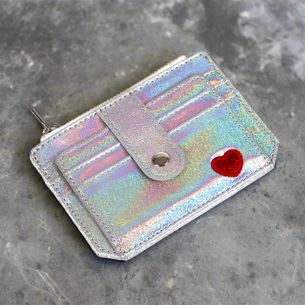 A showcasing of the Silver Glitter Wallet with a little red heart empty to showcase all the slots and pockets on the front of the wallet laying down on a countertop.