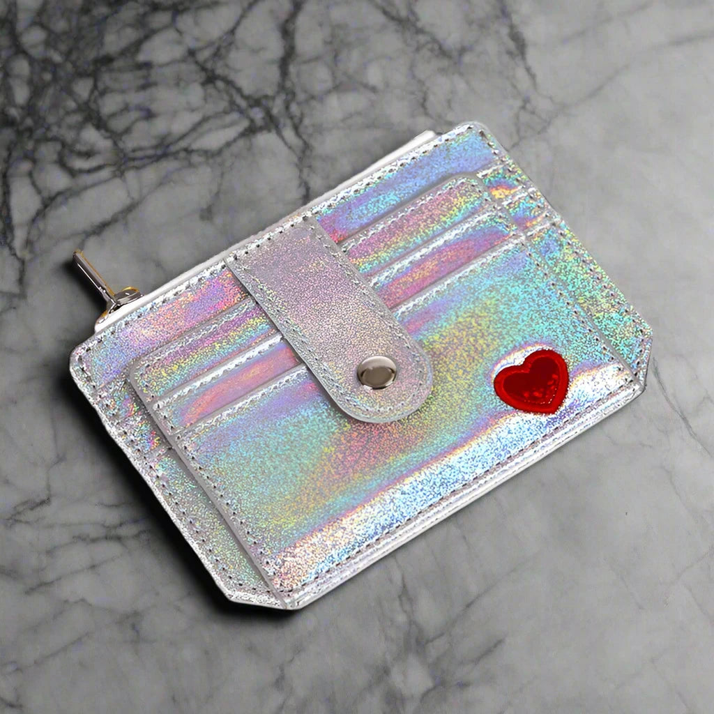 A showcasing of the Silver Glitter Wallet with a little red heart laid flat to show the front of the wallet. 