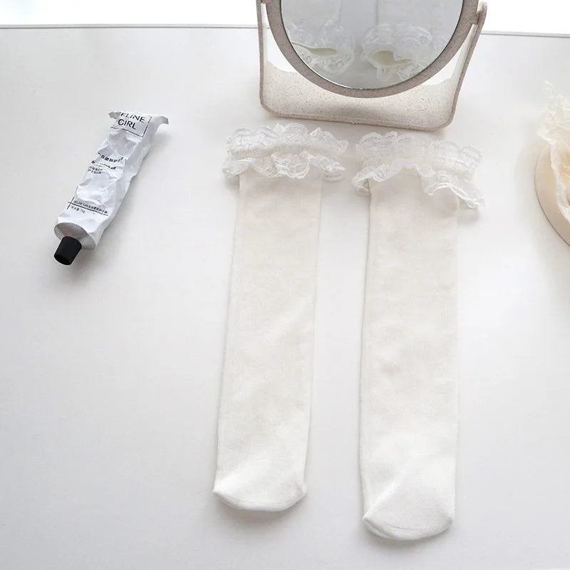 A showcasing of the White Lace Ruffle Socks laid out on a white table to give speculation to the pure whiteness of the socks. 